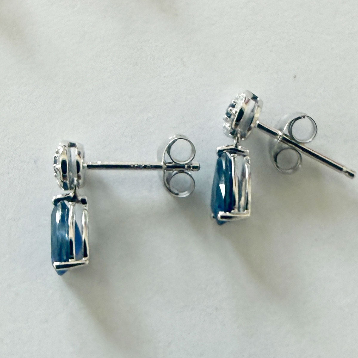 Aretes en oro blanco 10K con círculo de diamantes y centro de zafiro con gota de zafiro colgante