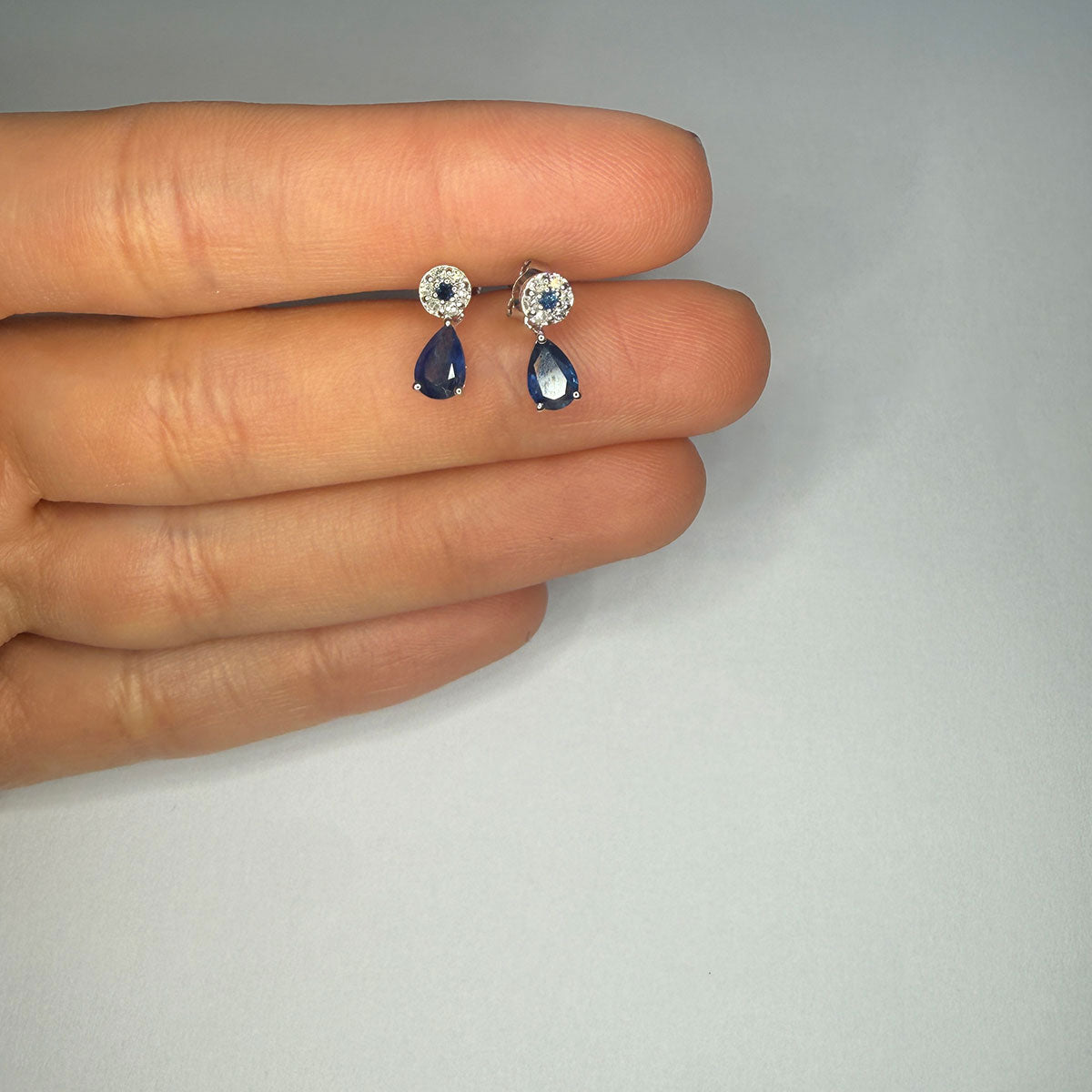 Aretes en oro blanco 10K con círculo de diamantes y centro de zafiro con gota de zafiro colgante