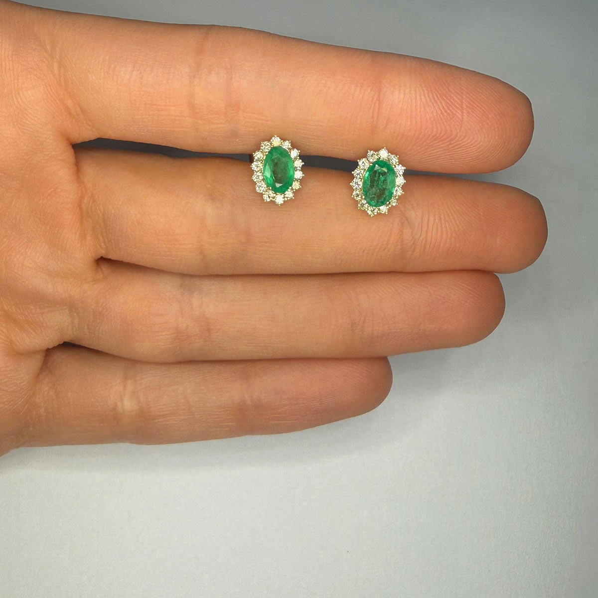 Aretes en oro amarillo 10K con esmeraldas ovaladas y halo de diamantes 0.30ctw