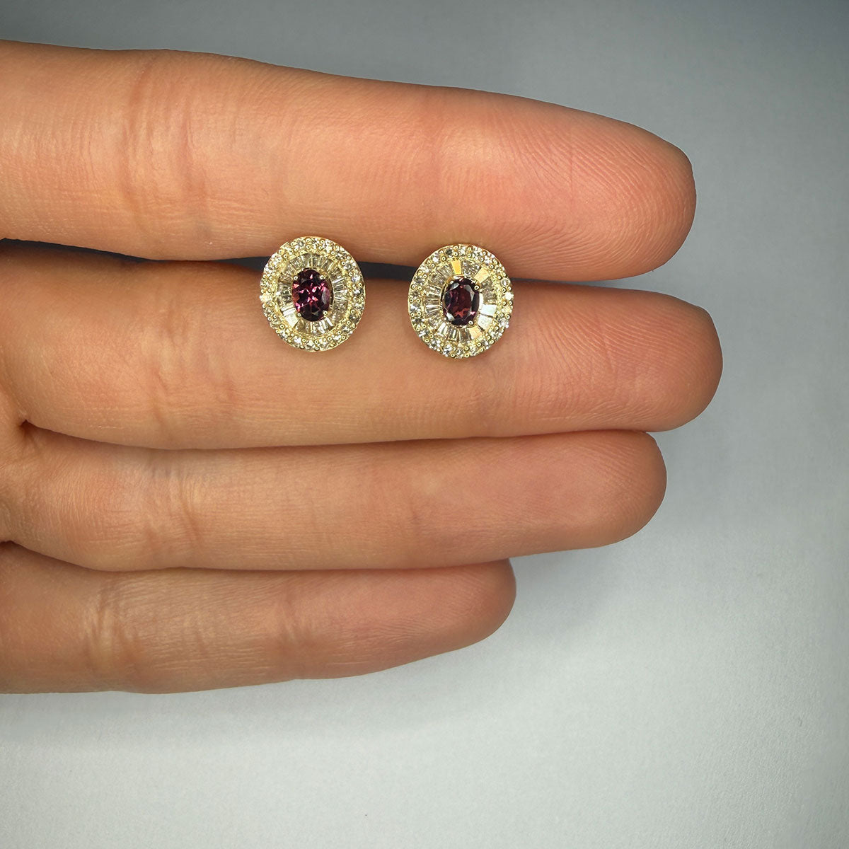 Aretes en oro amarillo 10K con granate ovalado y halo de diamantes redondos y baguettes 0.40ctw