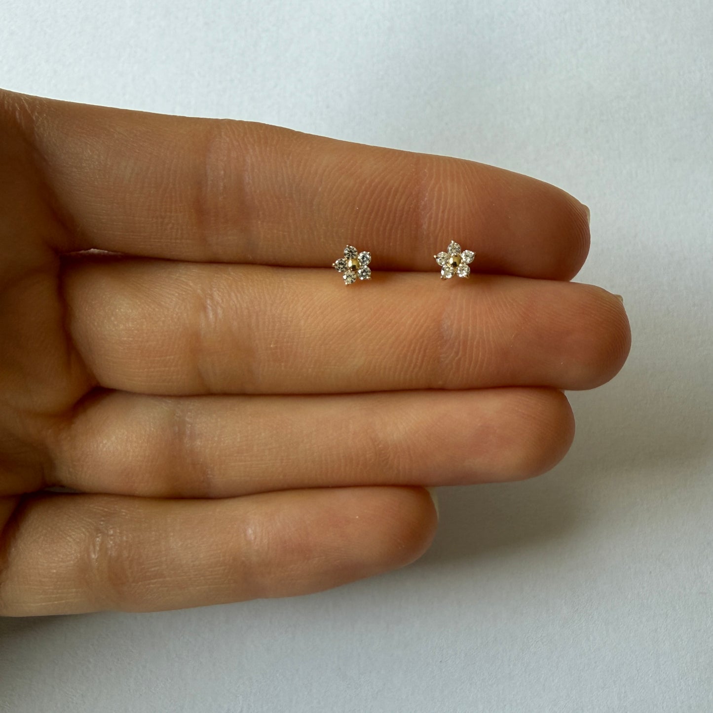 Aretes flor con cinco pétalos de circones blancos en oro amarillo 14K con tope rosca