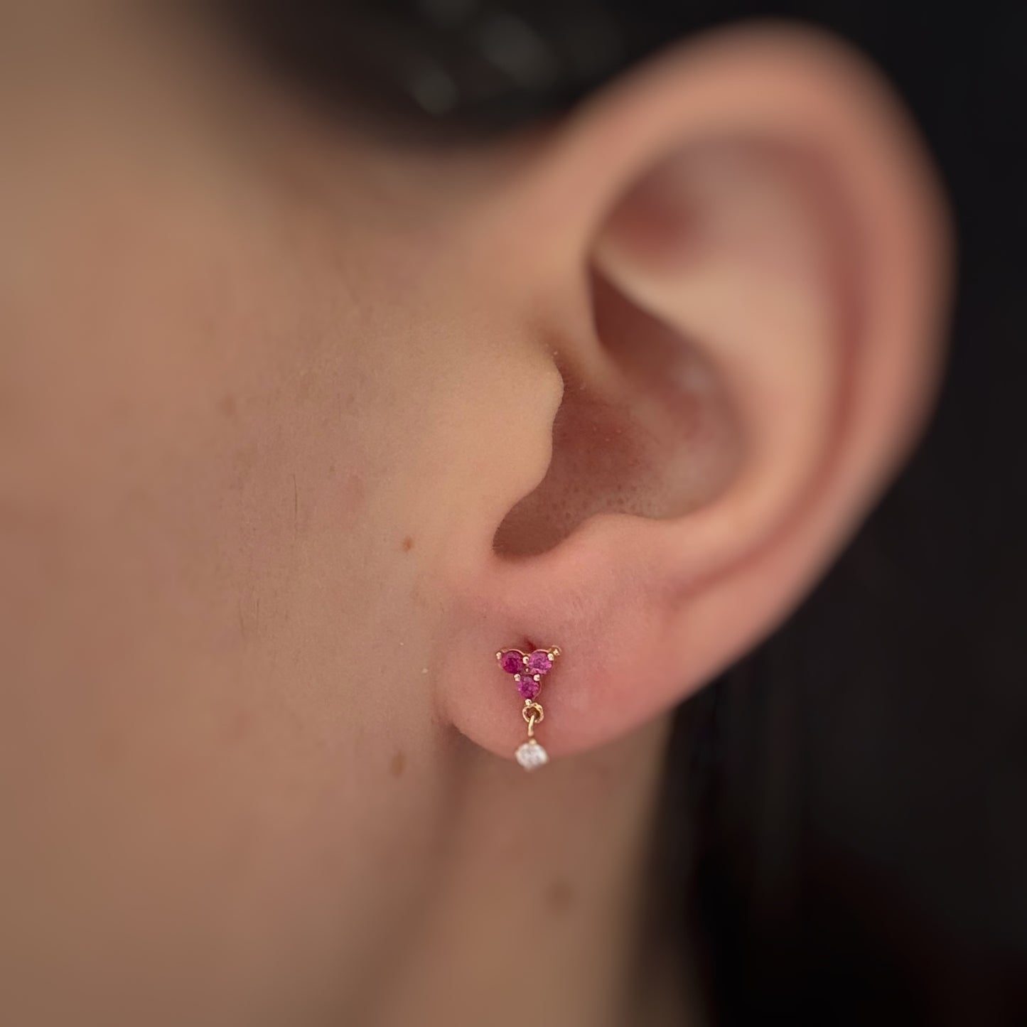 Arete con tres circonitas fucsia y una circonita colgante en oro amarillo de 14K con tope rosca