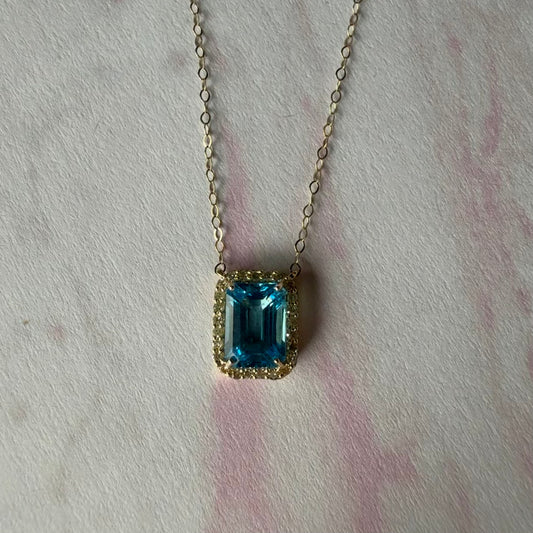 Collar en oro amarillo 10K con topacio azul y halo de diamantes 0.11ctw