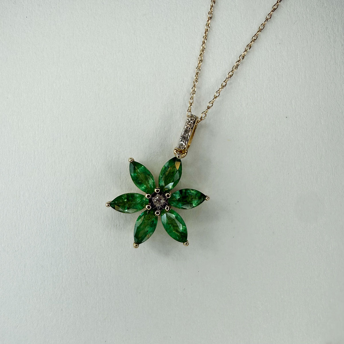 Collar flor de seis pétalos con esmeraldas en oro amarillo 10k