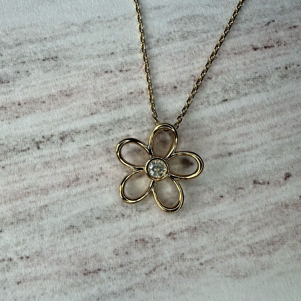 Collar flor delinada con diamante 0.10ct en el centro en plata con baño de oro amarillo
