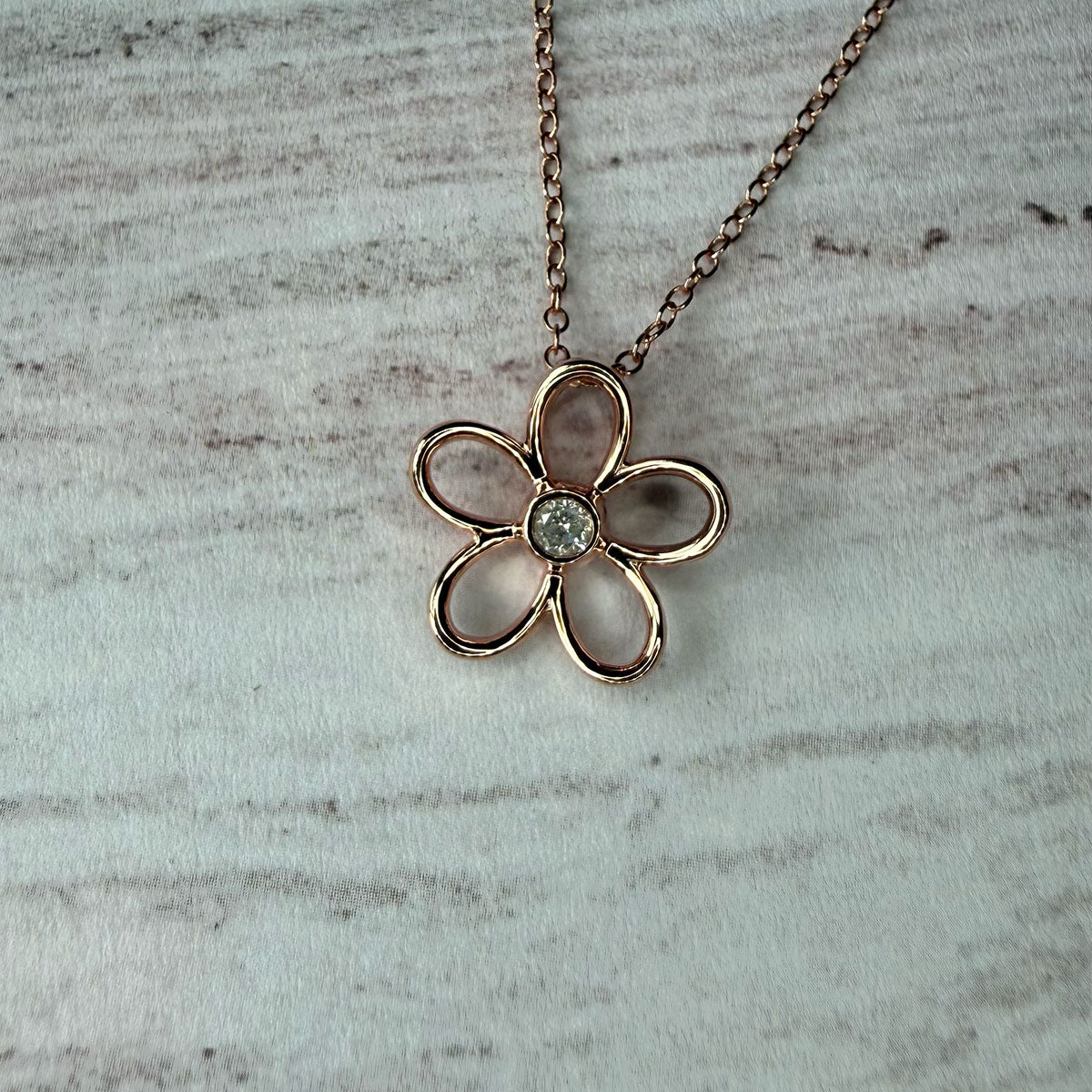 Collar flor delinada con diamante 0.10ct en el centro en plata con baño de oro rosa