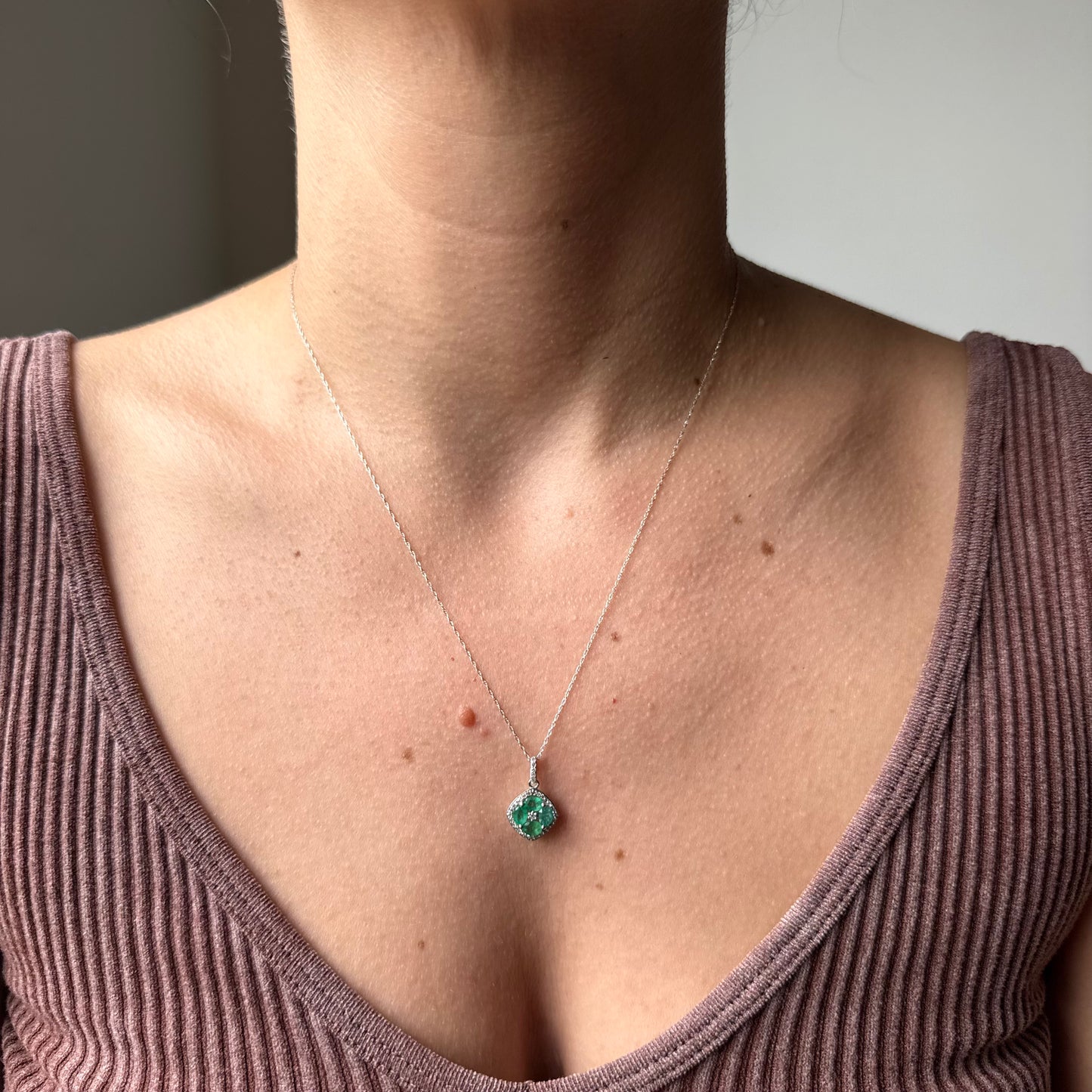 Collar en oro amarillo 14k con dije de esmeraldas en forma de flor y borde de diamantes 0.15ctw