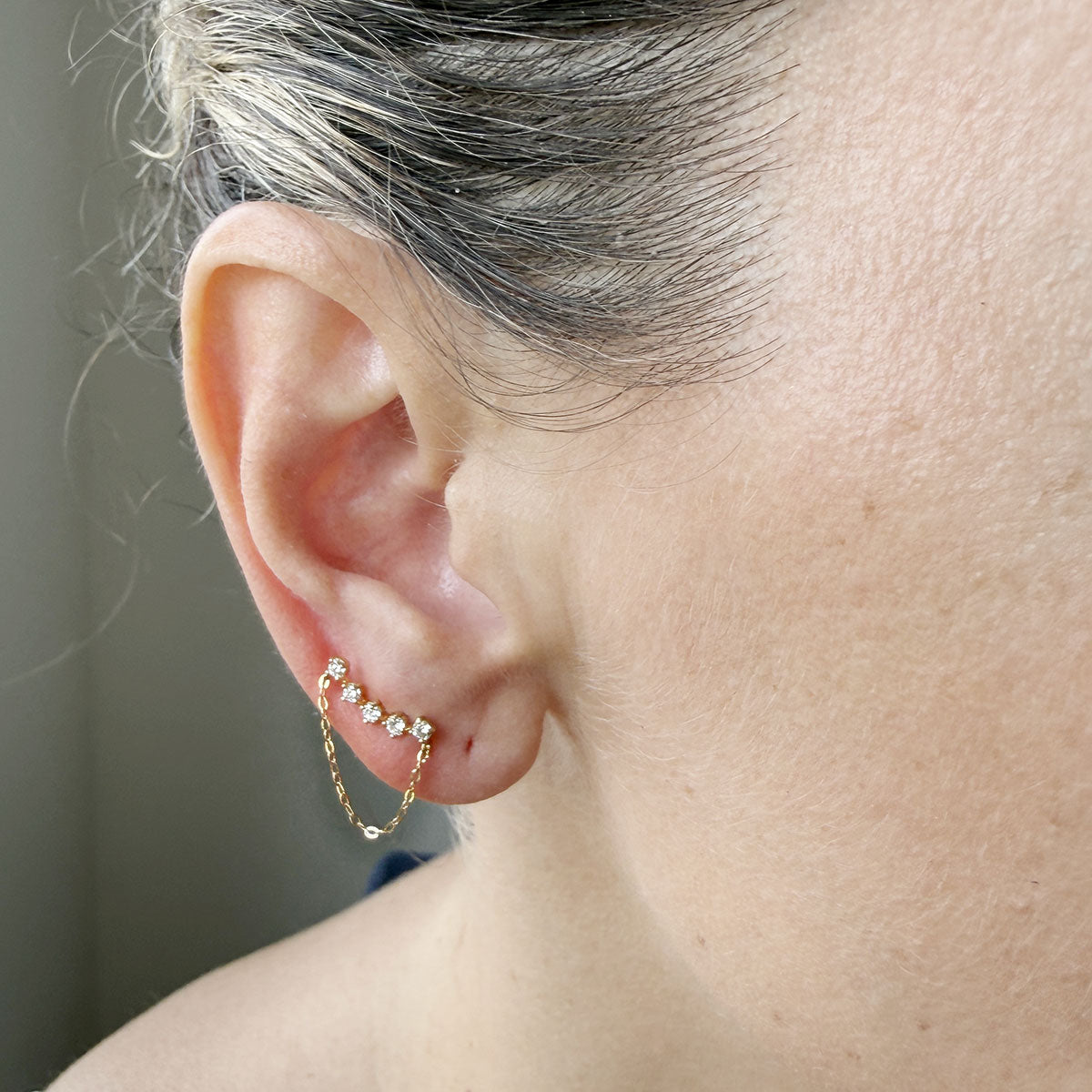Arete curva de cinco diamantes de laboratorio con cadena en oro amarillo 18k