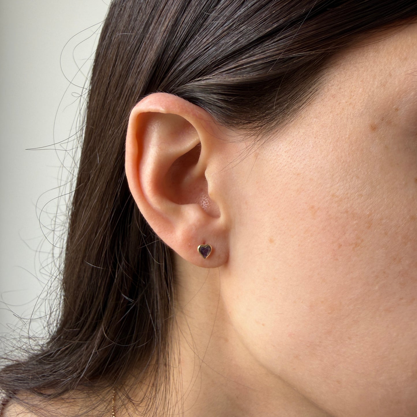 Aretes en oro amarillo 14k con corazón de circonita morada biselado con tope rosca