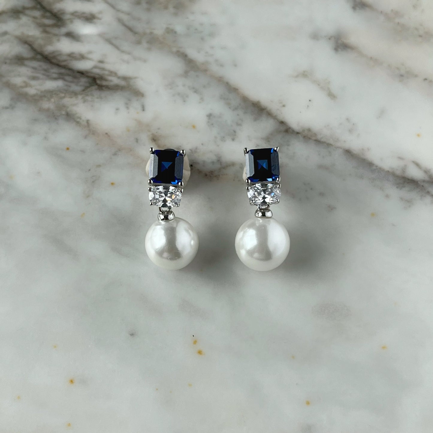 Aretes en plata con baño de platino con circonita azul y perla de cristal