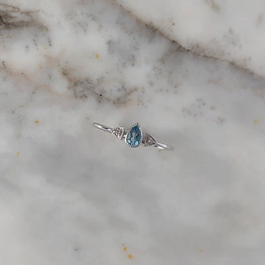 Anillo con Topacio azul en corte pera y diamantes en oro blanco 10k