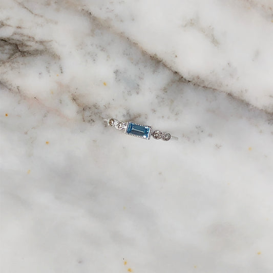 Anillo con topacio azul suizo en corte esmeralda y 0.10ctw de diamantes en oro blanco 10k
