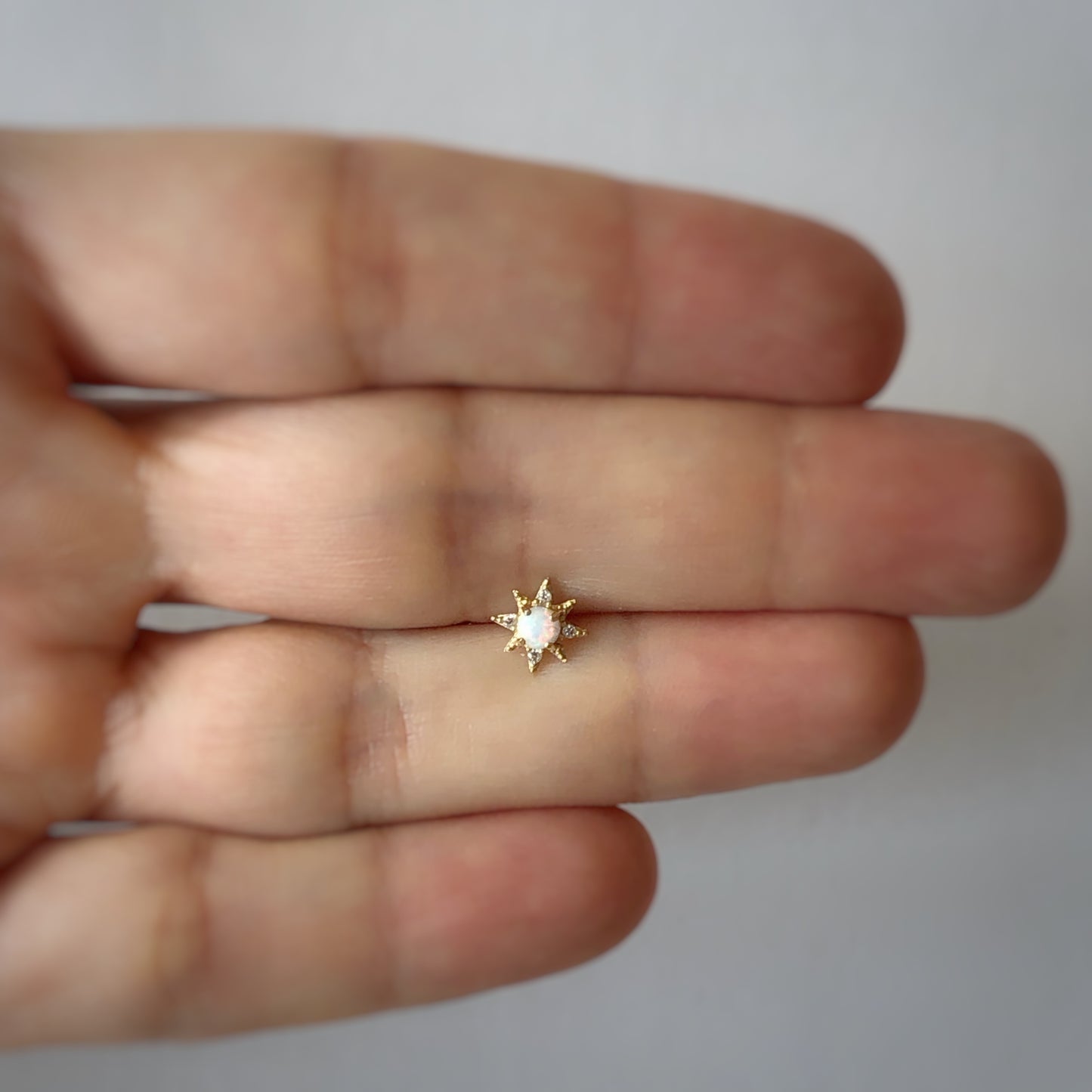 Arete piercing single de estrella polar con opalo blanco y circonitas en oro amarillo de 14k